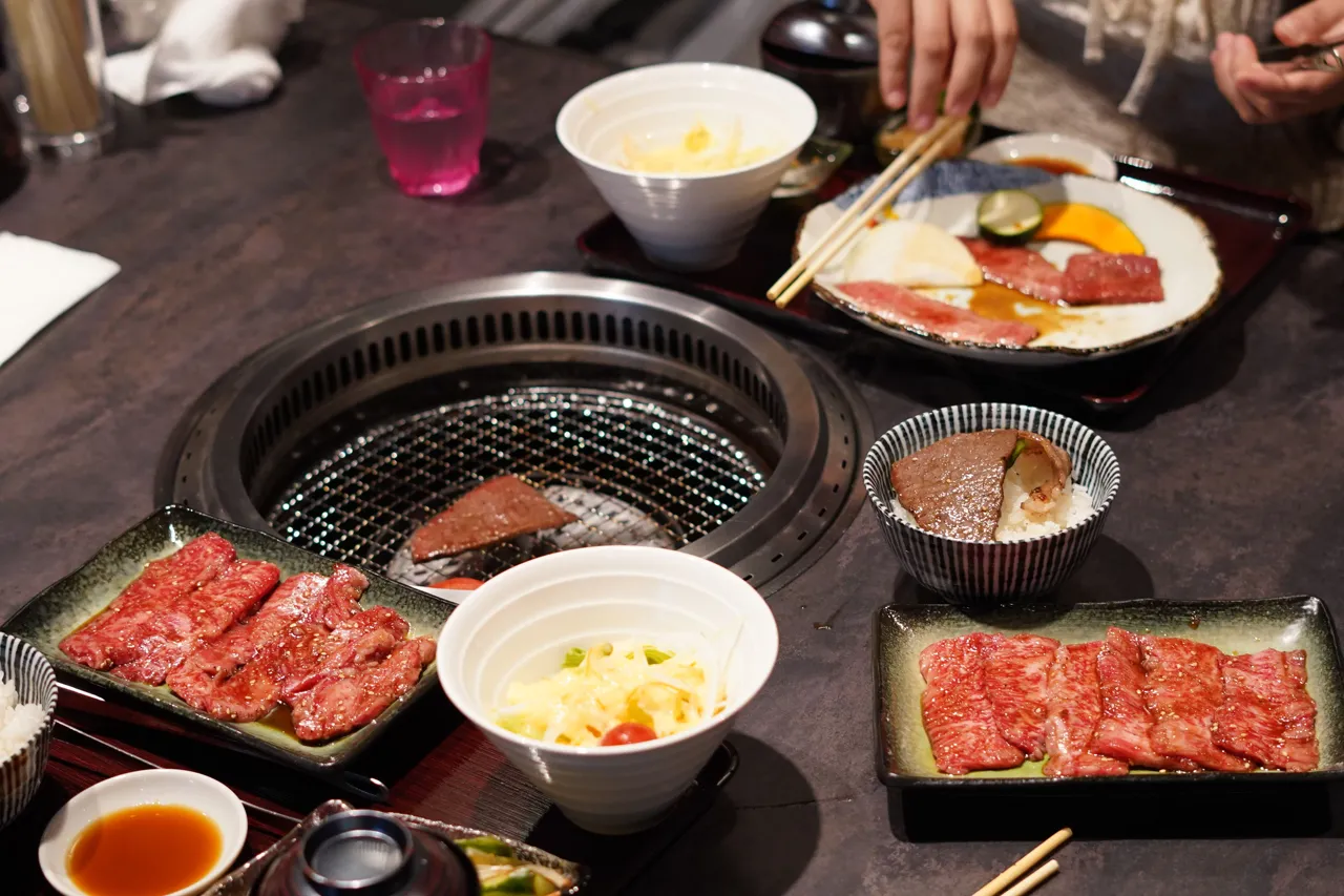 焼肉のイメージ。網で焼いた肉とサイドディッシュが並ぶ焼肉のテーブル