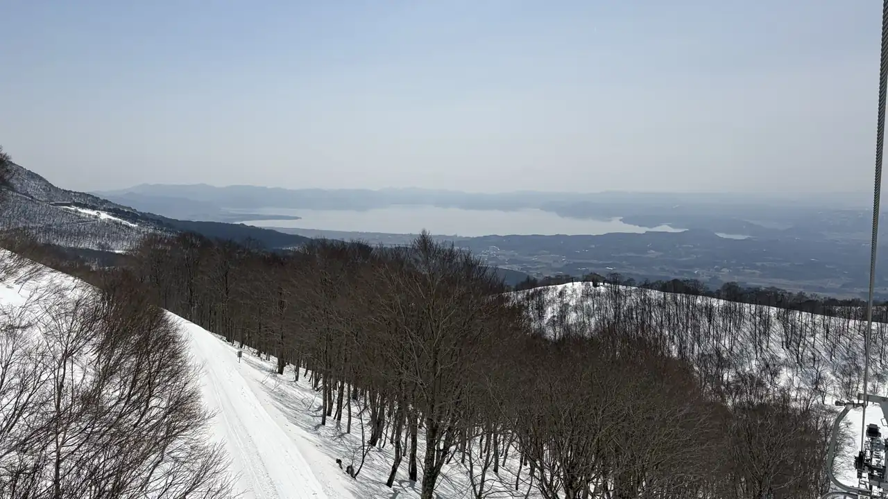 リフトから見た雪山の景色と遠くに見える湖